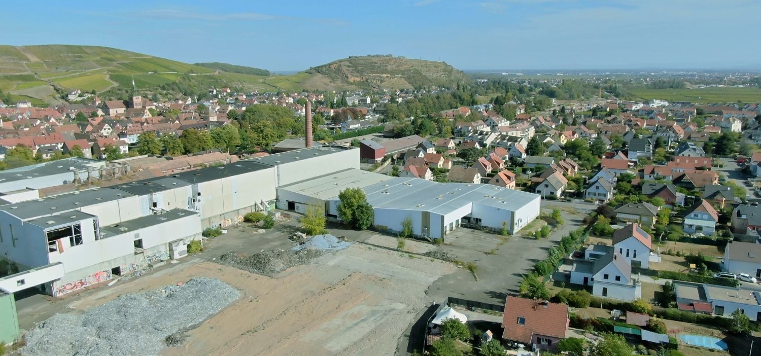 Vue aérienne d’une ancienne friche industrielle au cœur d’un quartier résidentiel en Alsace, future zone de réaménagement par Terre & Développement
